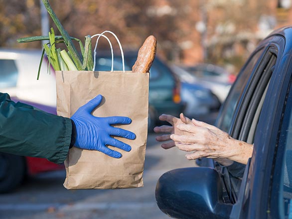 volunteer handing out grocery to elderly woman