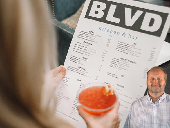 Woman holding a drink and looking at a restaurant menu with Mike Bindrup
