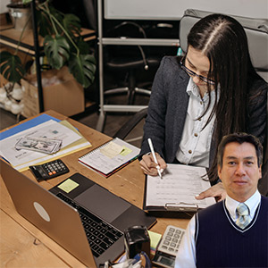 Woman working at a desk with computer, calculator with Juan Salas