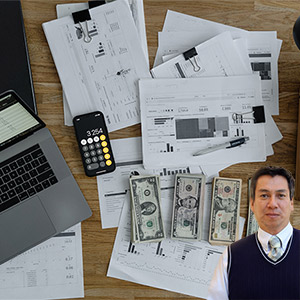 Desk full of paperwork, calculator and cash with Juan Salas