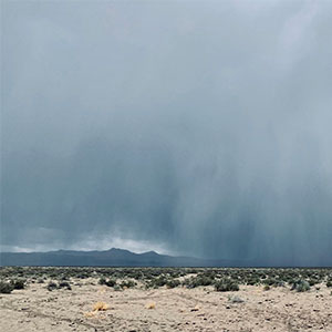 A storm rains on a dry Nevada rangeland that is barren in spots.