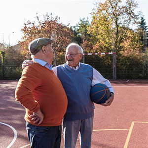 Two older men stopping to talk after a basketball game