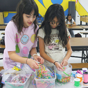 Two girls in 4-H making a beading project.