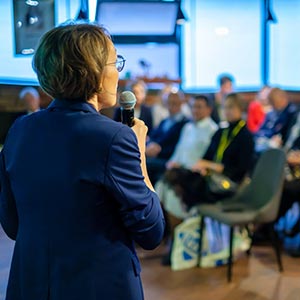 women speaking to crowd of people