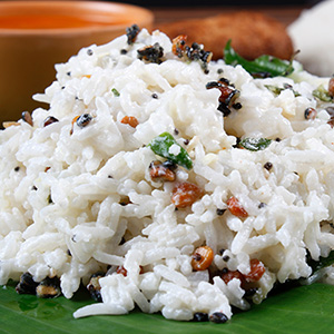 A scoop of white rice with some brown grains
