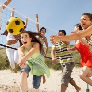 A group of people playing volleyball on beach.