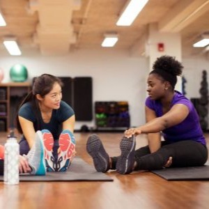 Two women stretching together on the floor.
