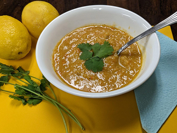 white bowel with tan colored soup and green garnish