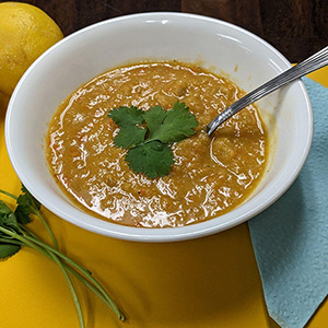 white bowel with tan colored soup and green garnish