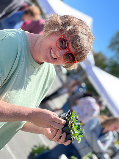 A woman showing off some plants during the UNR extension master gardener plant sale.