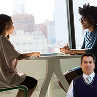 Two women sitting at a table having a discussion with Juan Salas