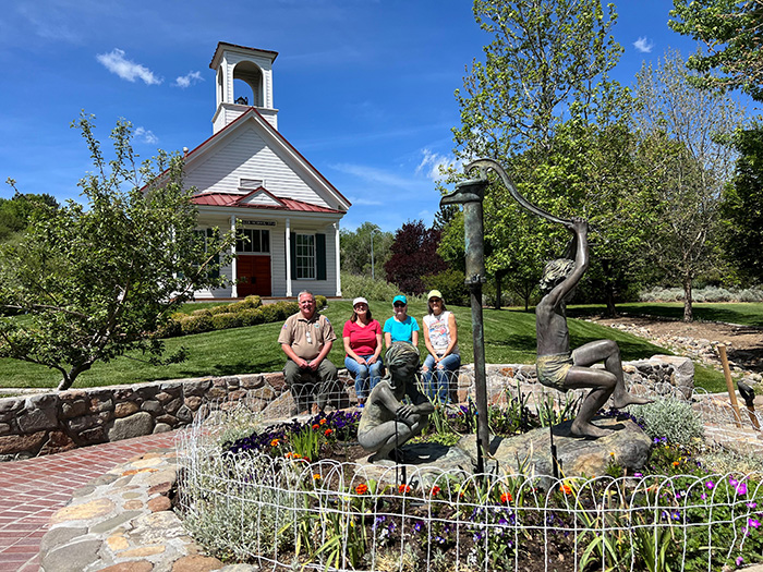 Four people standing in front of historic huffaker school at bartley ranch.