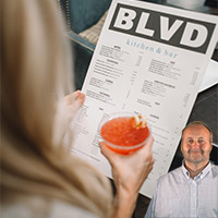 Women browsing a menu holding a drink with Mike Bindrup