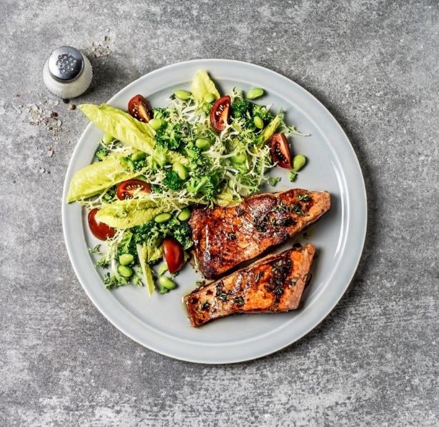 Serving size of salad and grilled salmon on a white plate.