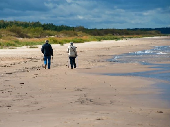 A couple walking on a sandy beach together. 