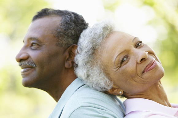 Black older couple leaning on each other. 