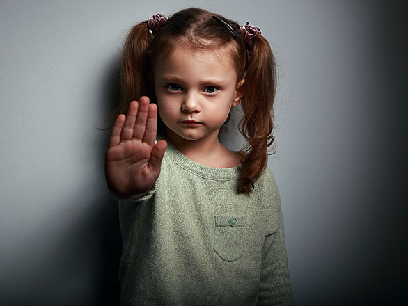A young child with pigtails holds her hand out in front of her as an indication to stop.