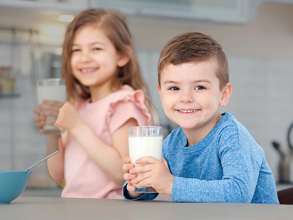 two kids drinking milk at the kitchen table