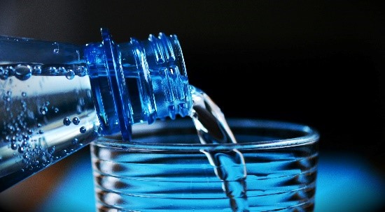 water poured into a glass from plastic water bottle