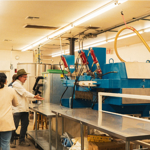 A man pointing to a food processor that makes apple cider