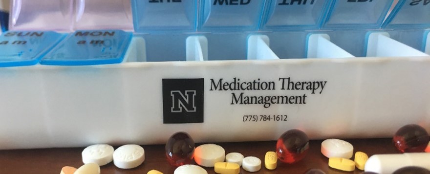 A pill container open with pills that reads Medication Therapy Management