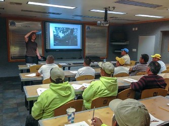 A group of men in yellow vests attending a class.