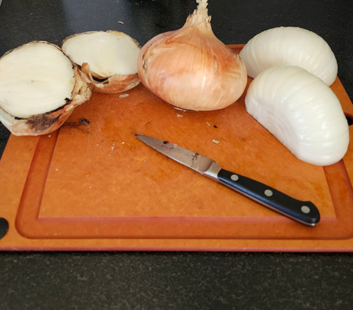 white onions on a cutting board and a knife.