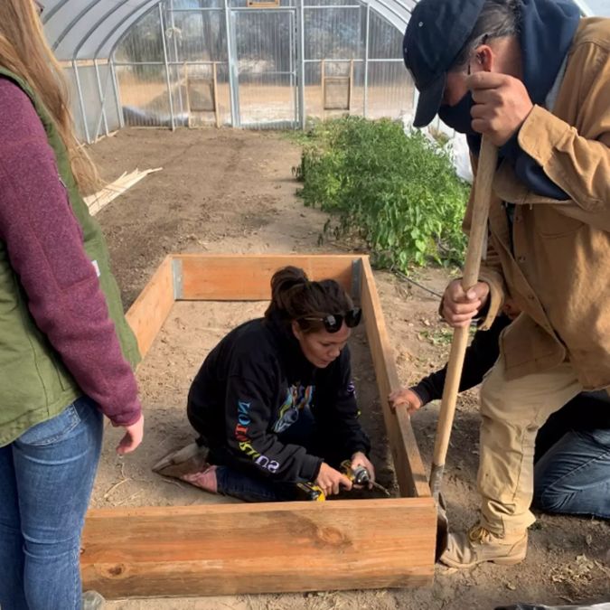 Team setting up planter bed in a greenhouse