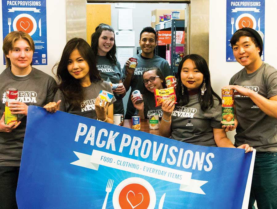 A group of students gathered around the Pack Provisions door, holding a banner and donations of food.