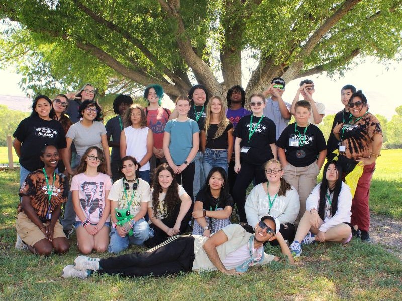 Kids and camp counselors posing for a picture in front of a tree