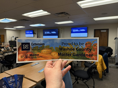 a hand holding a master gardener sign