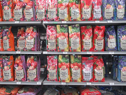 rows of bags of red and purple colored fertilizer bags.