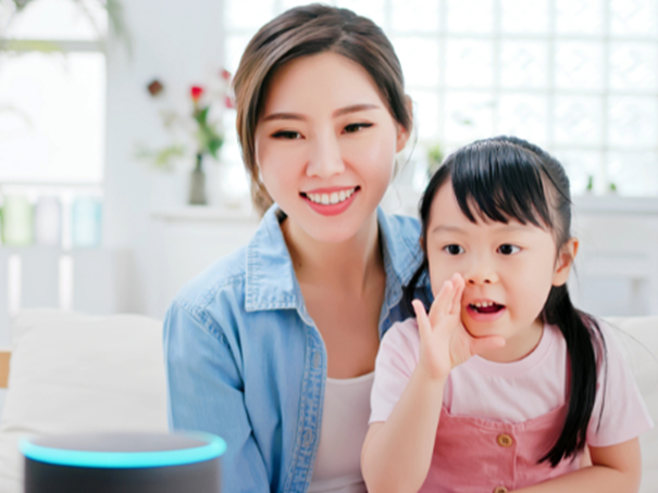 Mother and child speaking to Alexa, Alexa speaker has the blue ring light as it listens