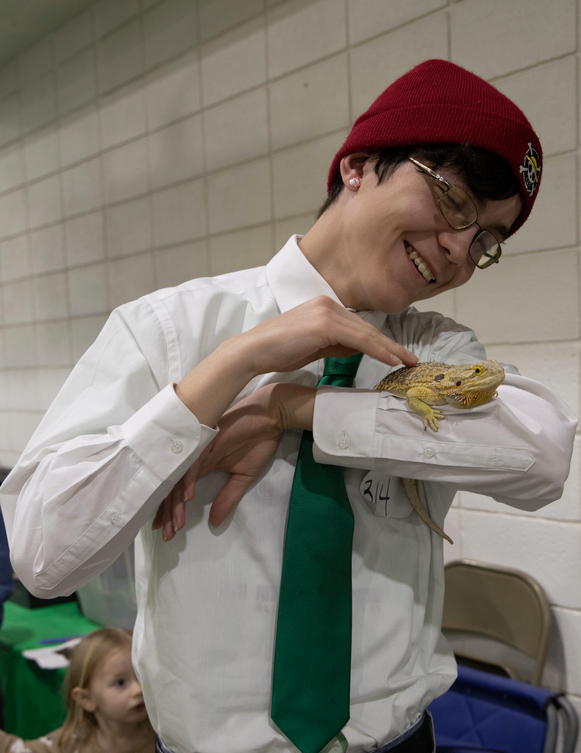 Teen holds a bearded dragon.