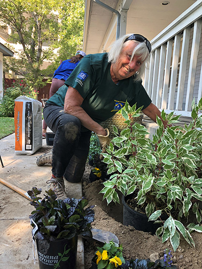 photo of a woman planting in front of a white fence
