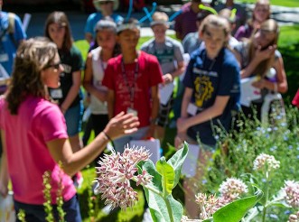 A group attends a class in a garden.