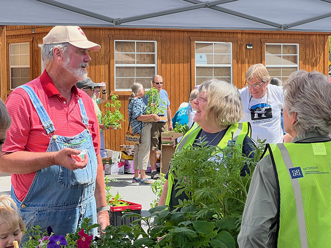 People standing outside talking around plants.