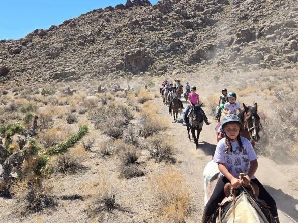 A picture of kids riding horses through the desert