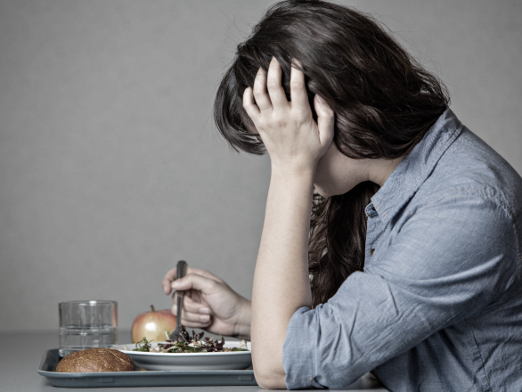 A woman feeling discouraged over her plate of food.