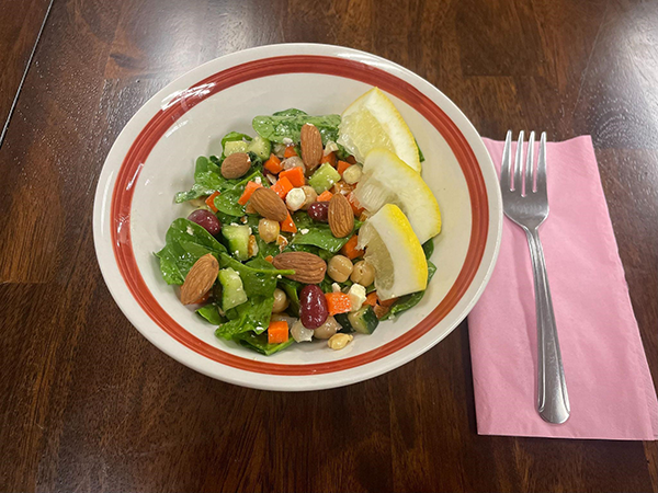 salad with vegetables and lemon wedges in a bowl and fork on the side.