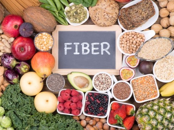 A picture of various foods that are rich in fiber with a sign in the middle that says fiber.