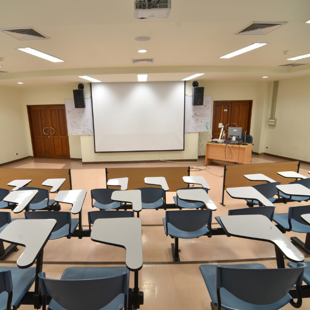 A photo of an empty classroom with chairs and a projector screen.