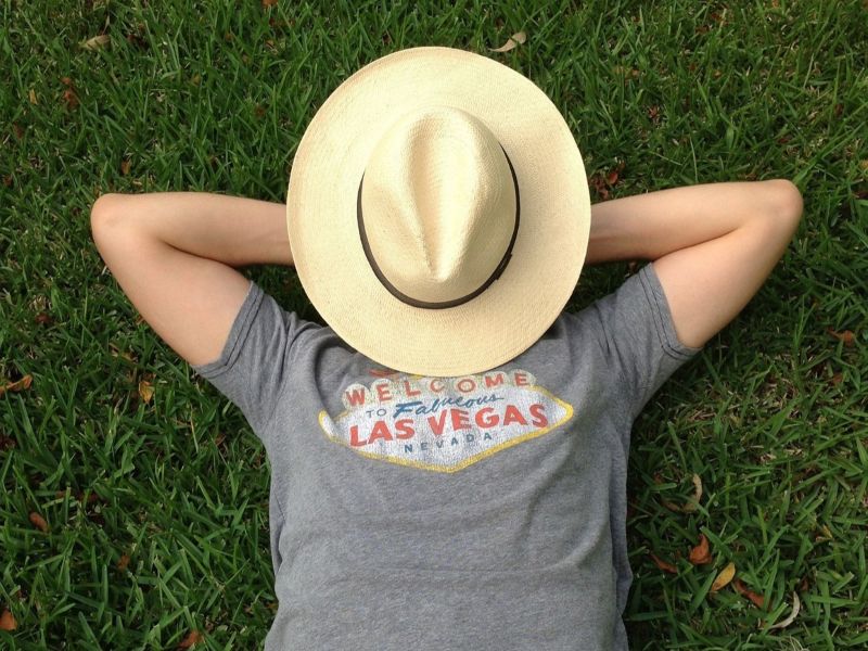 Relaxing on the grass with a hat over the face and a Las Vegas shirt on.