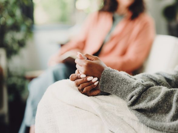 Two women sitting on a couch listening to one another.