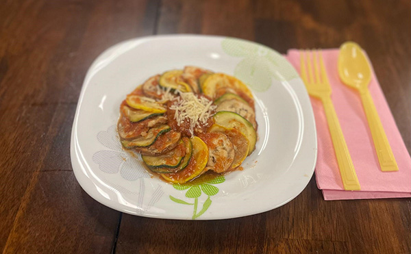 sliced vegetables on white plate with yellow silverware on the side with napkin