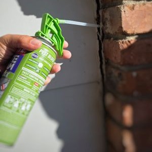 a person spray foams a large house gap