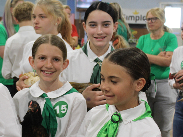Three girls smile as they hold their chickens for their showmanship contest.