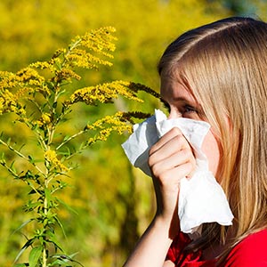 A girl covers her face with a tissue due to seasonal allergies