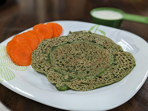 green colored pancakes and sliced carrots on side.