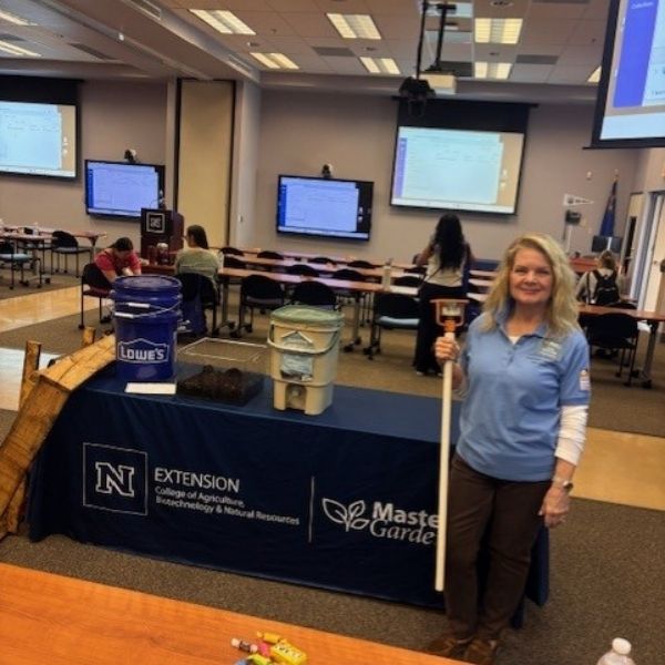 Master Gardener posing at conference with composting equipment